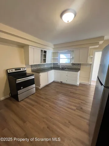 a kitchen with stainless steel appliances wooden floor and a sink