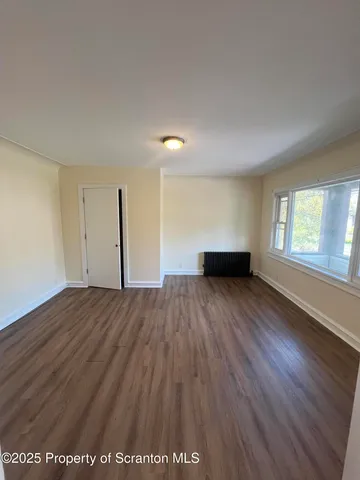 a view of empty room with wooden floor and window