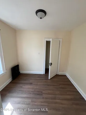 a view of an empty room with wooden floor and closet