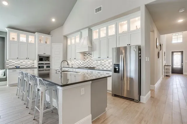 a kitchen with stainless steel appliances kitchen island granite countertop a refrigerator and a stove top oven