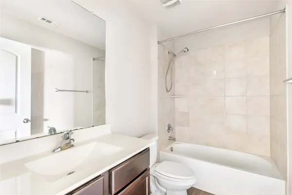 a bathroom with a bathtub shower sink vanity mirror and toilet