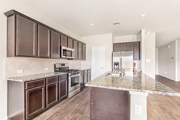 a kitchen with stainless steel appliances granite countertop a stove a sink and a microwave