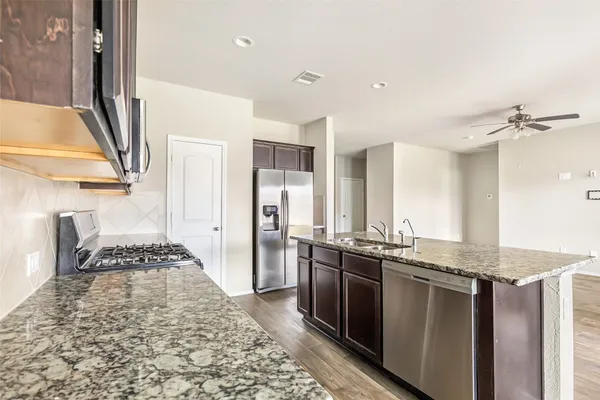 a kitchen with stainless steel appliances granite countertop a sink stove and refrigerator
