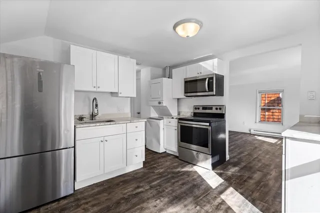 a kitchen with granite countertop a refrigerator stove and microwave