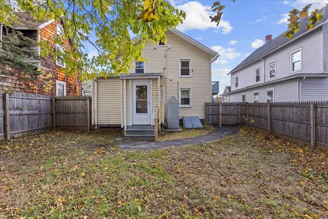 a view of a backyard with wooden fence and a large tree