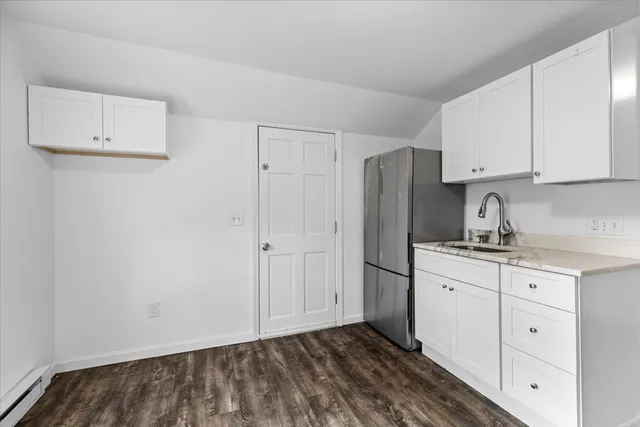 a kitchen with granite countertop white cabinets and refrigerator