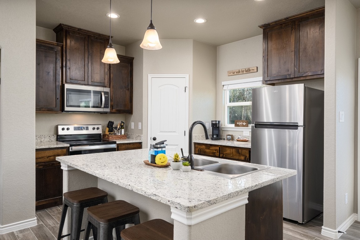 117 Lightning Bolt Spring Branch, TX 78070 - Photo 5 of 12 a kitchen with stainless steel appliances granite countertop a dining table chairs refrigerator and microwave