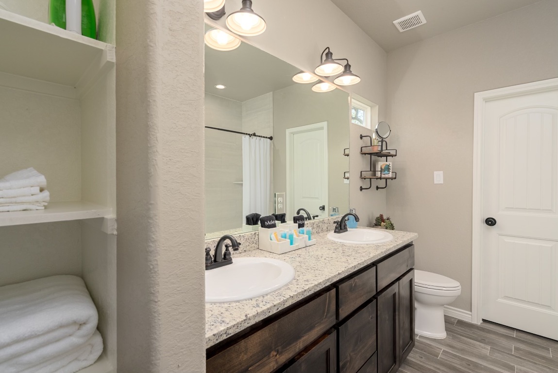 117 Lightning Bolt Spring Branch, TX 78070 - Photo 8 of 12 a bathroom with a granite countertop sink a toilet and a mirror