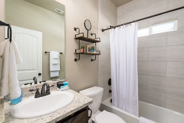 a bathroom with a granite countertop sink toilet and shower
