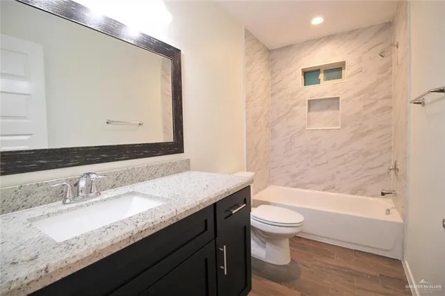 a bathroom with a granite countertop sink a toilet and a bathtub