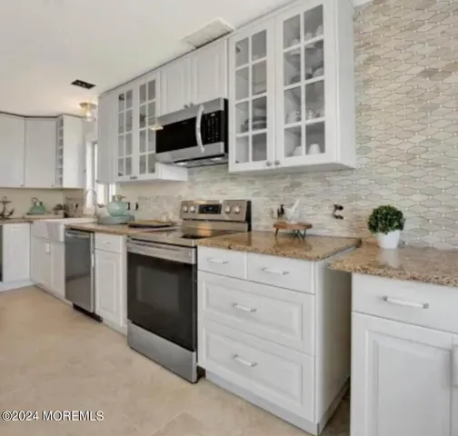 a kitchen with stainless steel appliances granite countertop a stove a sink and a microwave