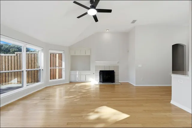 a view of empty room with wooden floor and fireplace