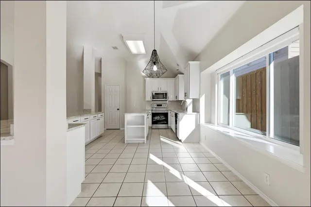 a large white kitchen with cabinets and chairs