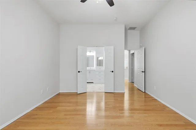 a view of an empty room with wooden floor and a bathroom