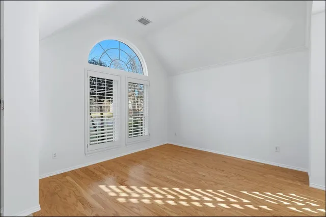 a view of empty room with window and wooden floor