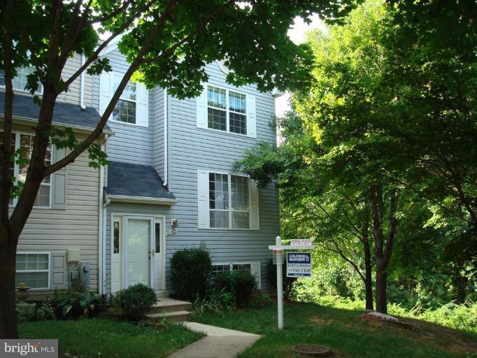 a front view of a house with a garden and trees