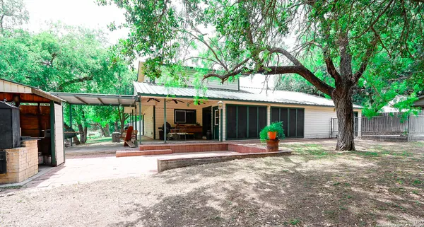 a view of a patio with table and chairs under a large tree