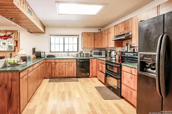 a kitchen with stainless steel appliances granite countertop a refrigerator a sink dishwasher a stove with wooden cabinets and floor