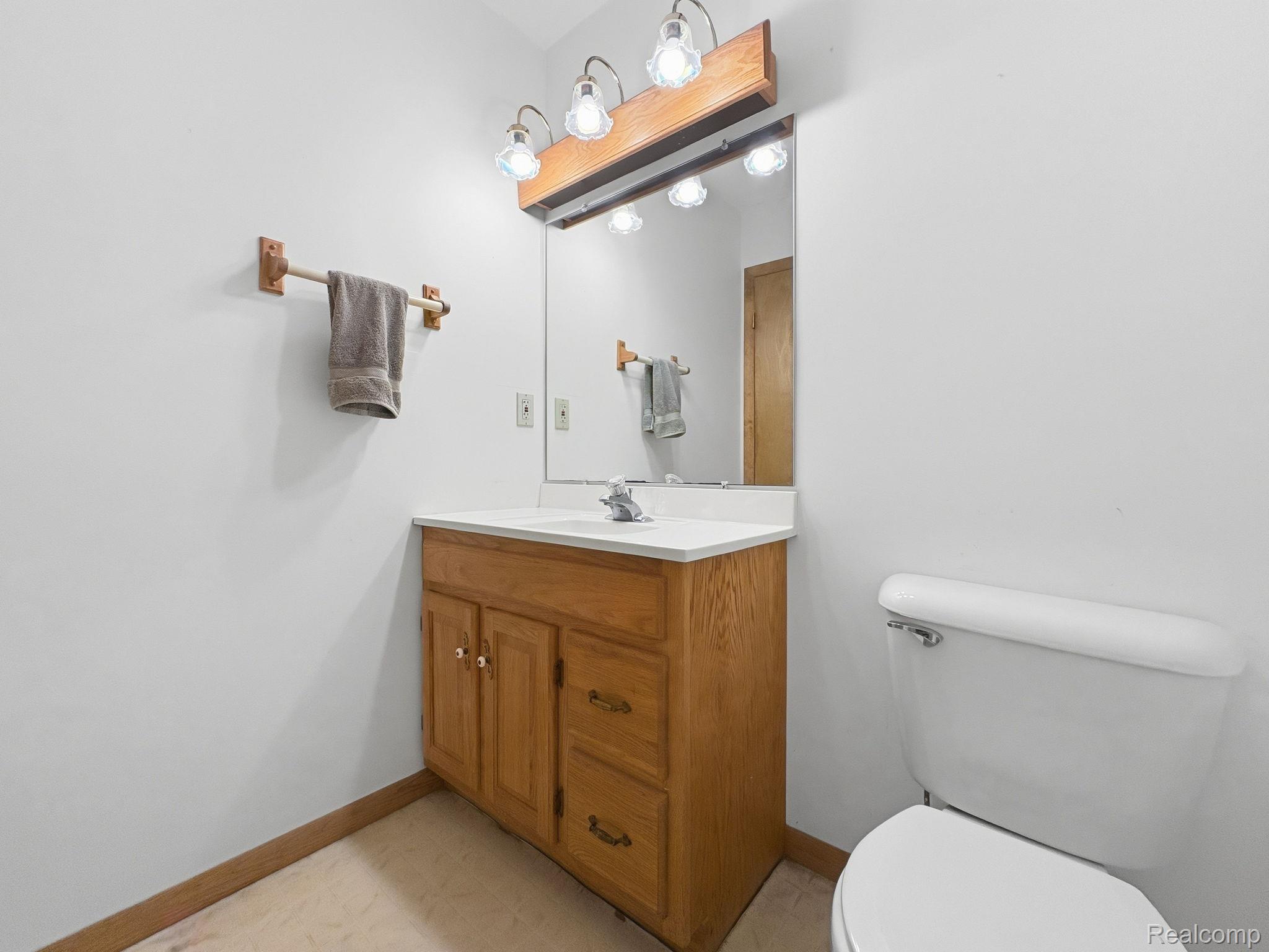 2259 Kassuba Road Gaylord, MI 49735 - Photo 22 of 46 Single vanity with wood-finish cabinetry, integrated sink, and wall-mounted mirror