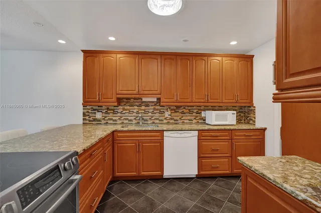 a kitchen with stainless steel appliances granite countertop a sink a stove and a refrigerator