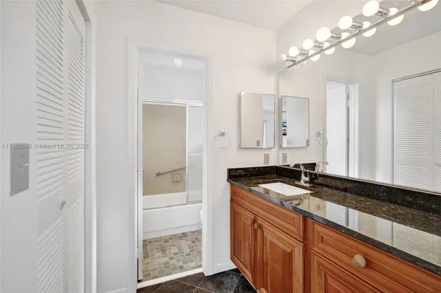 a bathroom with a granite countertop sink a mirror and a shower