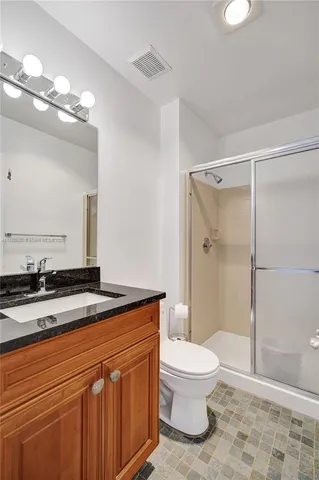 a bathroom with a granite countertop sink mirror vanity and toilet