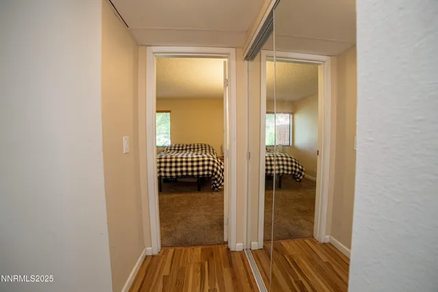 a view of a hallway with wooden floor and a bathroom