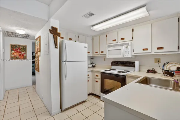 a kitchen with stainless steel appliances a refrigerator a stove a sink and white cabinets