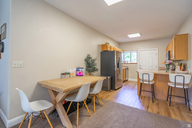 700 North Main Street, Unit F3 Washington, UT 84780 - Photo 13 of 34 Open-concept kitchen and dining area featuring warm wood-finish flooring, a breakfast bar with seating, light wood cabinetry, and stainless steel appliances
