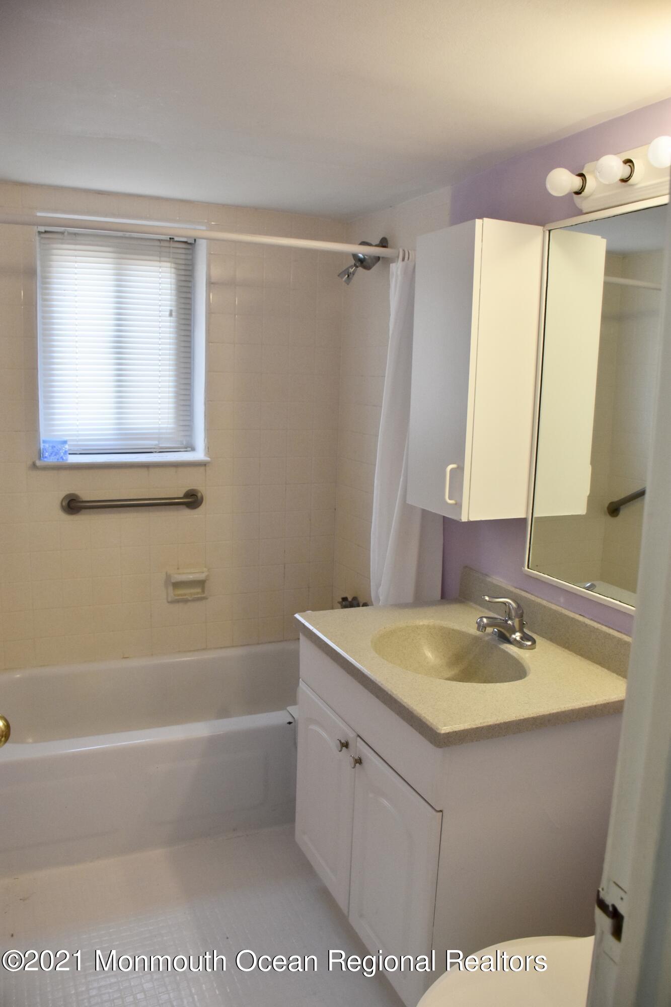1000 River Road, Unit 3J Belmar, NJ 07719 - Photo 8 of 19 a bathroom with a sink a mirror and a bathtub