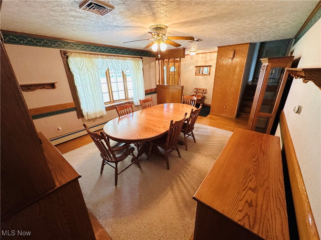 1684 Morris Street Mineral Ridge, OH 44440 - Photo 22 of 50 Dining space featuring a textured ceiling, a baseboard heating unit, a ceiling fan, and wood finished floors