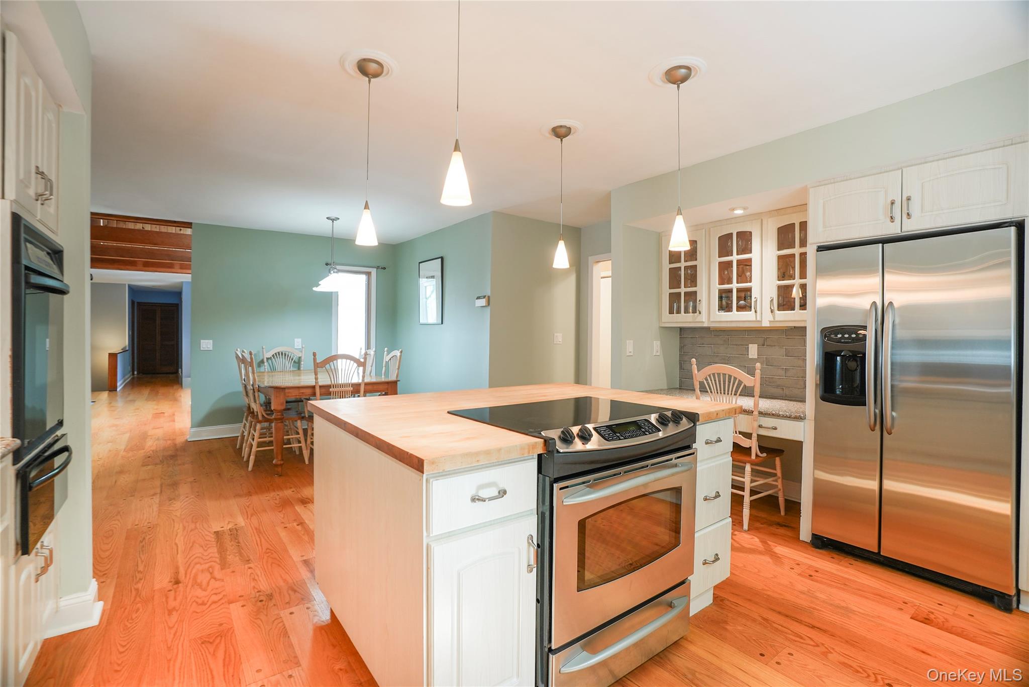 22 Peters Lane Pound Ridge, NY 10576 - Photo 13 of 43 Kitchen featuring a central island with wood-finish countertop, stainless steel range, and three pendant lights