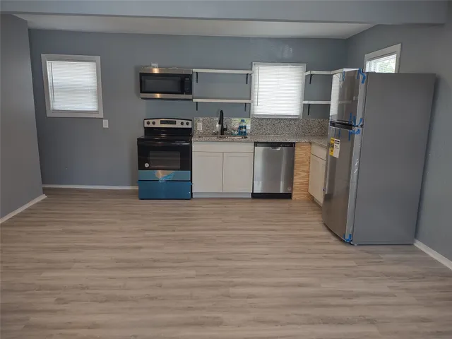 a kitchen with granite countertop a refrigerator and a stove top oven