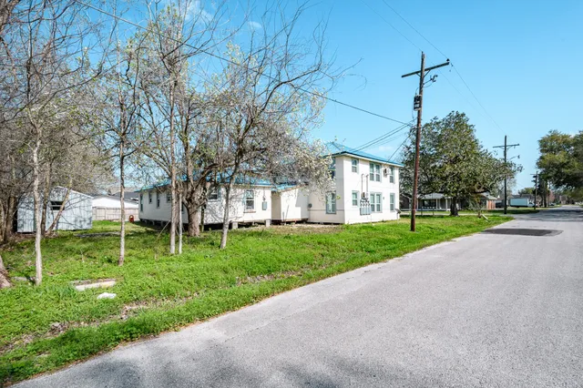 a front view of a house with garden and trees