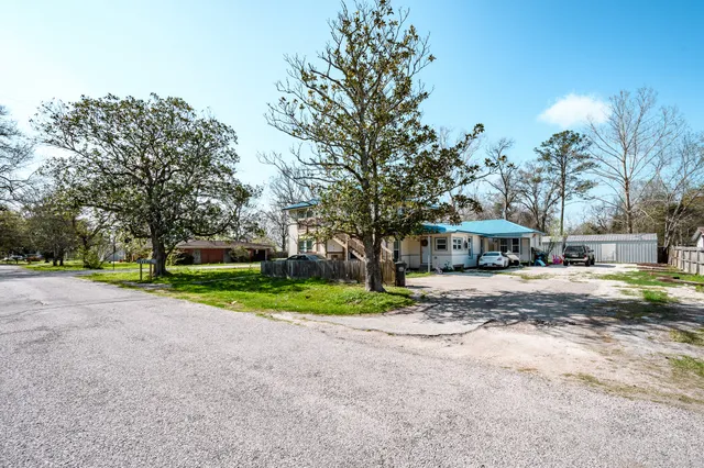 a view of a house with a yard and large trees
