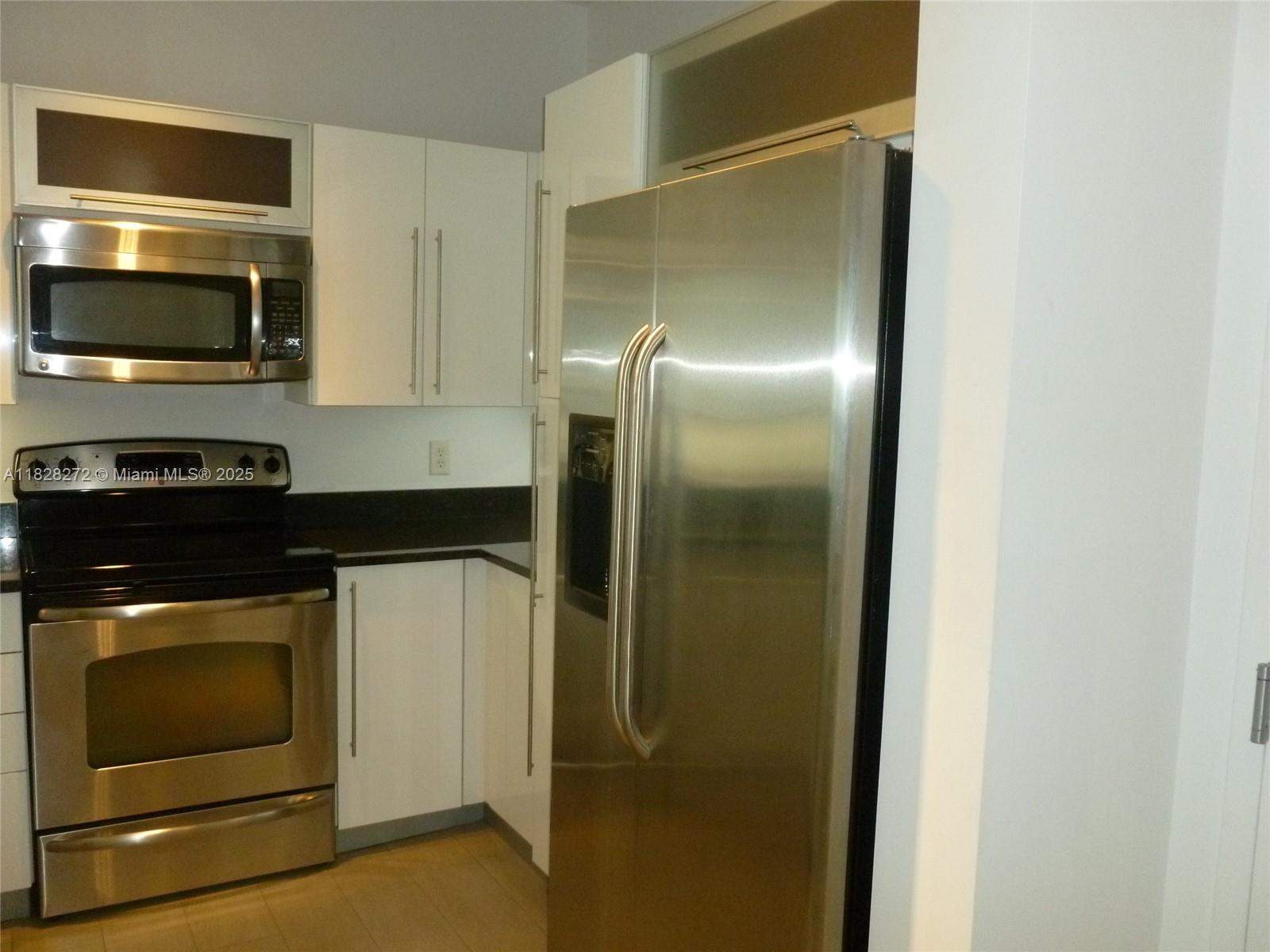 7350 Southwest 89th Street, Unit 808S Miami, FL 33156 - Photo 6 of 13 a kitchen with stainless steel appliances granite countertop a refrigerator and a stove top oven