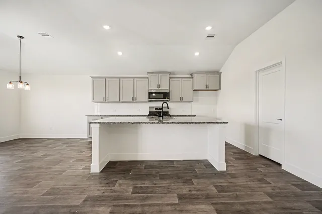 a view of kitchen with granite countertop stainless steel appliances cabinets a sink and a counter top space