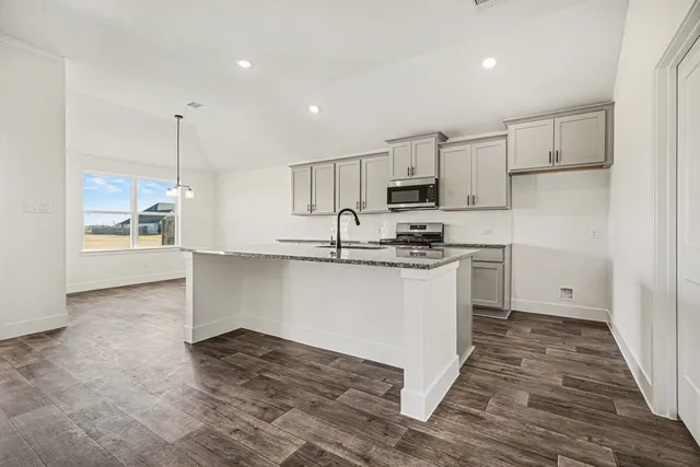 a kitchen with granite countertop a stove a sink and a refrigerator