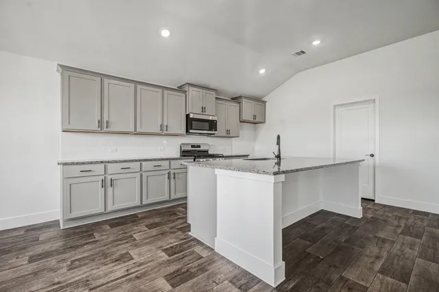 a kitchen with kitchen island a sink stove and white cabinets