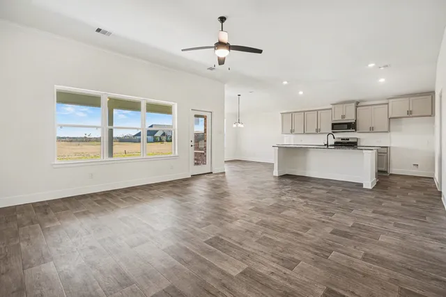 a view of a kitchen with a stove cabinets a ceiling fan and wooden floor