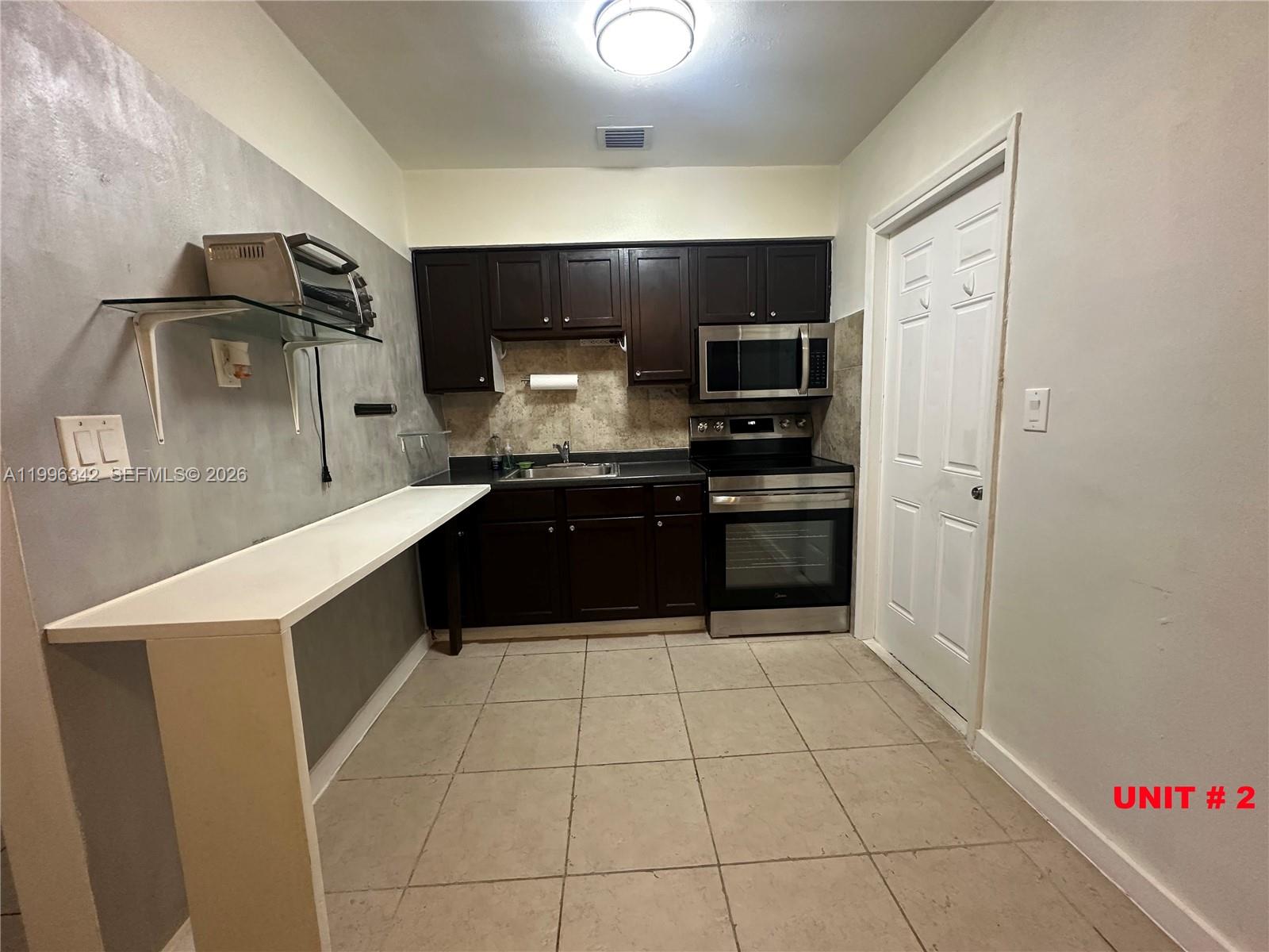 809 Northeast 2nd Street, Unit 2 Hallandale Beach, FL 33009 - Photo 5 of 8 a large kitchen with a stove a refrigerator and a sink