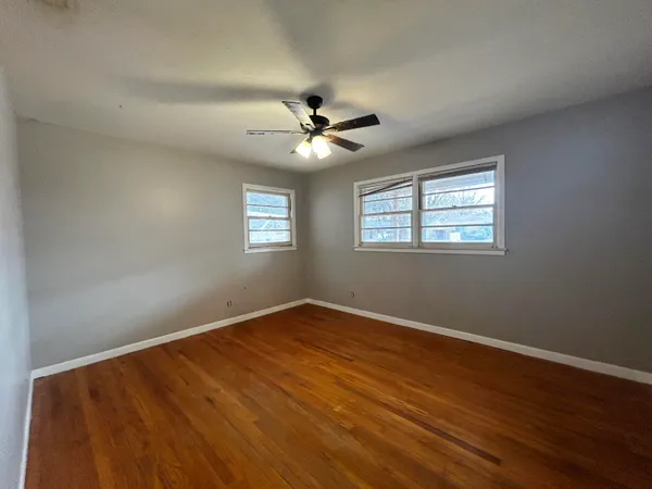 a view of an empty room with chandelier fan and a window