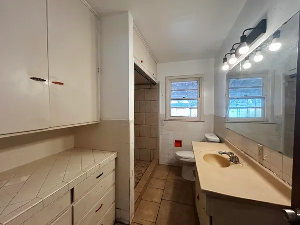 a bathroom with a sink and mirror with bathtub
