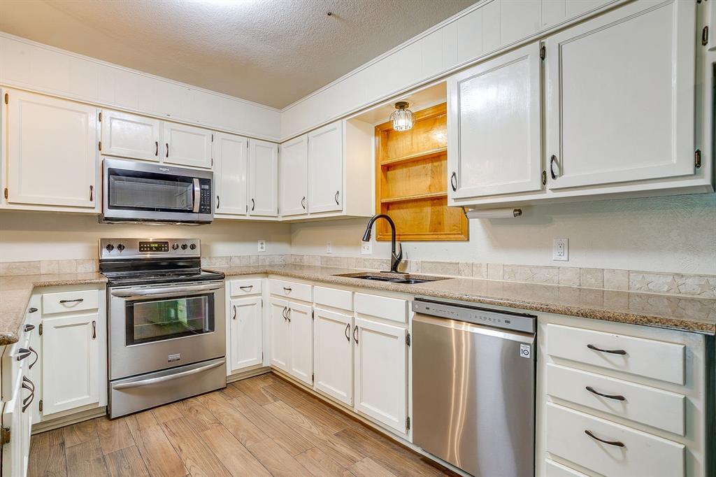 709 North Ave B Springtown, TX 76082 - Photo 11 of 32 a kitchen with granite countertop cabinets stainless steel appliances and a sink