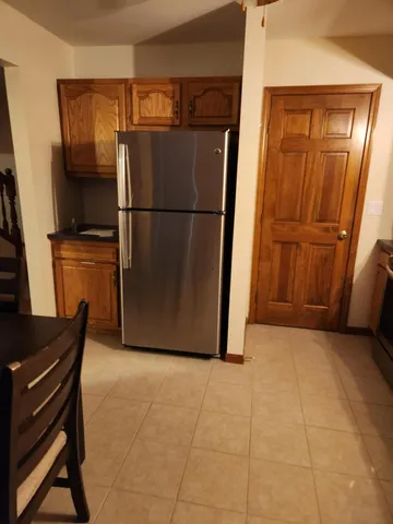 a view of a refrigerator in kitchen and an empty room