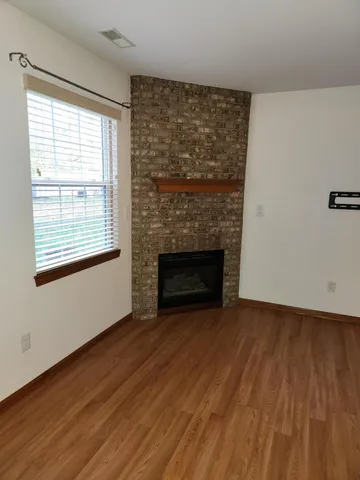 an empty room with wooden floor fireplace and windows