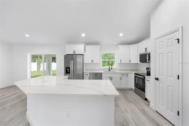 a large kitchen with kitchen island a sink stainless steel appliances and cabinets