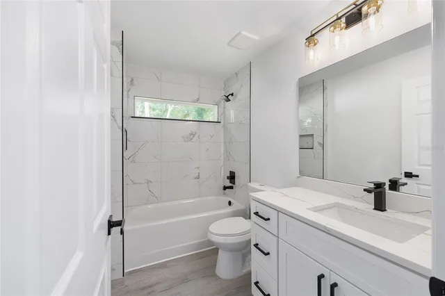 a bathroom with a granite countertop sink a toilet and shower