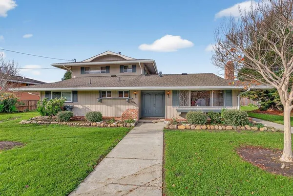 a front view of a house with a yard and potted plants