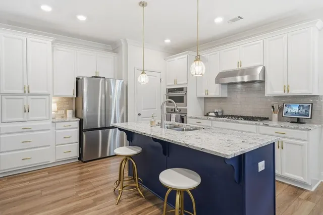 a kitchen with stainless steel appliances granite countertop a stove a sink and a white cabinets